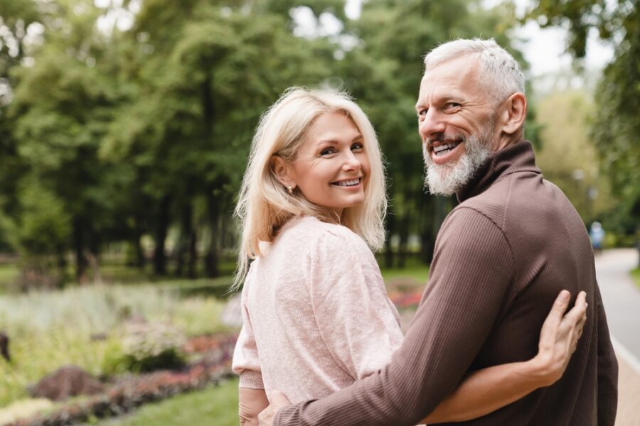 An elderly couple enjoys a walk in the park, smiling while embracing each other - migraine