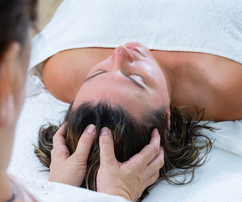 A person receives a relaxing head massage while lying on a spa bed, wrapped in a towel - Tension headache